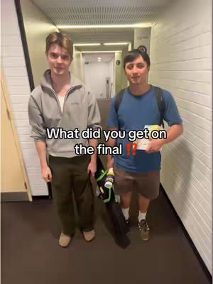 Two young men stand in a hallway, facing the camera. The man on the left is wearing a gray hoodie and dark green pants, while the man on the right has a blue shirt and khaki shorts. Text overlayed on the image asks, "What did you get on the final??"