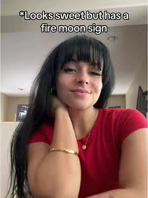 A woman with long dark hair and a red shirt smiles slightly, resting her hand on her neck, with text overlaid at the top.
