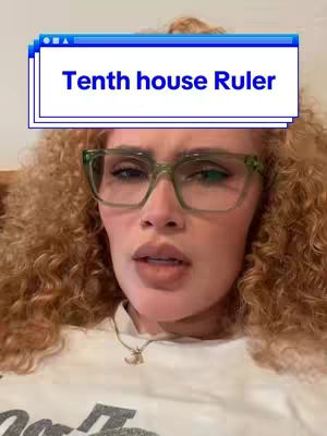 A close-up shot of a woman with curly red hair wearing green-framed glasses and a white t-shirt. A text overlay reads 'Tenth house Ruler' in a blue box, set against a background that seems to be indoors. The woman looks towards the bottom of the frame, and is slightly out of focus.