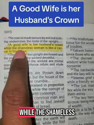 The image shows a close-up shot of a person's finger pointing to text within an open book, with a text overlay at the top that reads, 'A Good Wife is her Husband's Crown'. The book's pages are yellowed, and the text is in black. The person's finger, with pink nail polish, is highlighting a specific line. A red and white text box rests at the bottom.