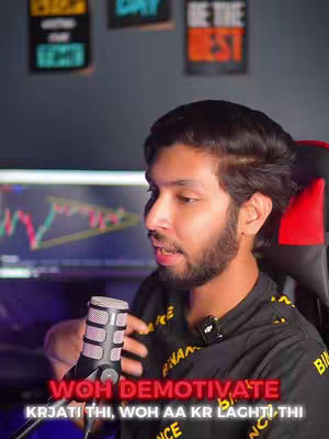 A man with a beard is speaking into a microphone. The background has computer monitors with trading charts and motivational posters. Text is overlaid at the bottom.
