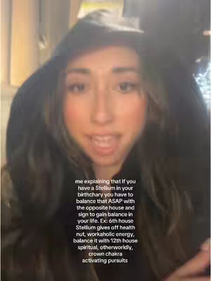 A woman with long, dark hair wearing a black hoodie sits in front of a blurred background. She is looking at the camera and speaking. Overlayed text provides details about astrology and birth charts.