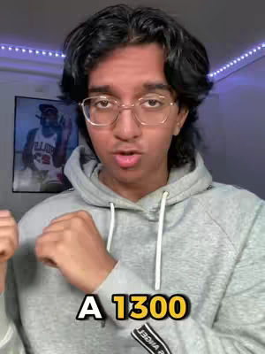 A close-up shot of a young man with glasses, wearing a grey hoodie, looking directly at the camera. Below, a text overlay reads \"A 1300\". Behind him is a poster of a basketball player.