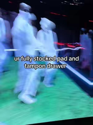 The image features blurred figures in white suits, suggesting a performance or event. Text overlaid reads:
"ur fully stocked pad and tampon drawer"