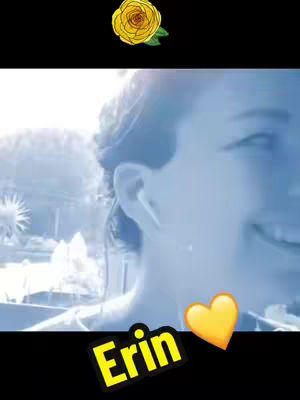 The cover image is a close-up shot, primarily in blue tones, featuring the side profile of a person’s face, with an earbud visible. In the upper left corner, there's a yellow rose illustration, and a bright yellow heart emoji is positioned near the bottom right. The name 'Erin' appears in a contrasting yellow and black text at the bottom left. The background is slightly blurred, suggesting an outdoor setting.