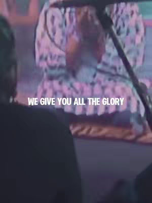 The cover image features the words 'WE GIVE YOU ALL THE GLORY' in white text against a blurred background of a performance. A person is seen from the back, wearing a patterned top, with their hands raised and a microphone visible in the frame.