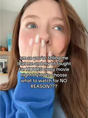 A close-up selfie of a woman with long brown hair, light skin, and blue eyes. Her right hand covers her mouth. Text overlays in white.
