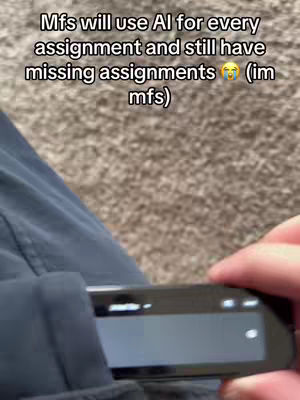 The image shows a person's arm and part of their torso with a pair of dark blue pants. The focus is on the pants pocket, where a black electronic device is partially visible. The background appears to be a light brown carpet. The text overlay at the top reads: βMfs will use AI for every assignment and still have missing assignments.β