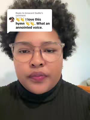 A close-up shot of a person with curly dark hair and glasses. A speech bubble in the top left corner contains text, and the person has a neutral expression.