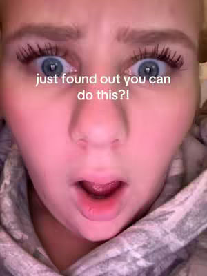 A close-up shot of a person's face with an expression of surprise. The person's eyebrows are raised, and eyes are wide with dilated pupils. Their mouth is slightly open, revealing a hint of the lower lip. The skin has a slightly pinkish hue, and the lighting appears soft and even.