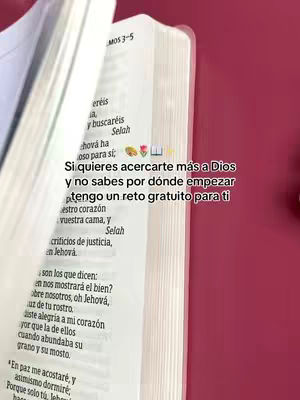 The image shows an open Bible with text on the pages. The pages are slightly curved, suggesting it's being held. Overlay text is placed on top, with some small graphics/emojis near the text.
