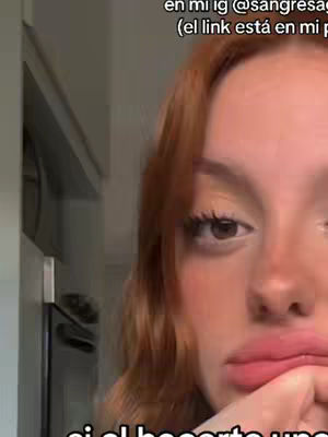 A selfie of a woman with reddish-brown hair, looking downwards with a slightly concerned expression. Her lips are visible. The background is blurred, suggesting an indoor setting.