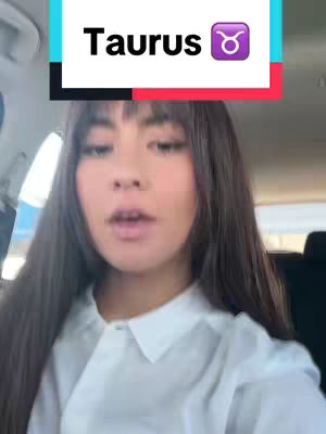 A selfie taken from inside a car. The main subject is a person with long, dark hair and a white collared shirt looking directly at the camera with a neutral facial expression. The top of the image features a colored banner that displays the word 'Taurus' alongside the Taurus astrological symbol.