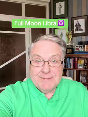The cover shows a man in a green polo shirt smiling at the camera. Overlaid on his head is a green banner with the text 'Full Moon Libra' and a Libra zodiac symbol. The background consists of a room with framed pictures and a bookshelf. The man is wearing glasses.