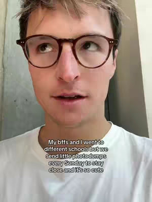 A man with light skin and short, light-brown hair wearing tortoiseshell glasses and a white t-shirt is looking up and slightly to the right. Text is added at the bottom of the screen.