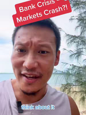 A man in a grey tank top is the focus of the image, with a red overlay above his head with the text 'Bank Crisis = Markets Crash?!'. The background shows a beach scene with water, sand, and some greenery.