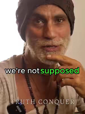 A medium shot of a man with a gray beard wearing a black beanie. The man is looking at the camera and gesturing with his right index finger while text overlays his image.