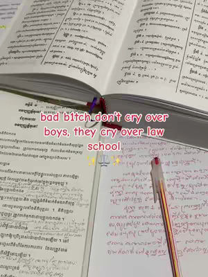 The image shows an open book with text, a notebook page with handwritten text, and a pen. Text overlayed says, "bad bitch don't cry over boys, they cry over law school."
