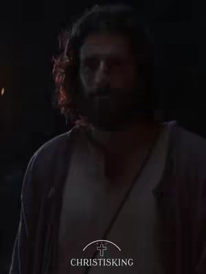 The image shows a man facing the camera with a slight downward angle, the background is dark. The man has dark, long hair, a beard and is wearing a white long-sleeve under a dark jacket. The logo "CHRISTISKING" is at the bottom of the image with a cross symboling the beginning of the brand name. The image is low-lit with a dark, foreboding atmosphere.