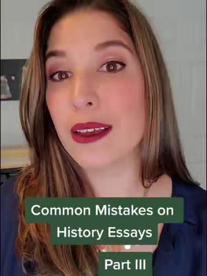 A woman with long brown hair and maroon lipstick is centered in the frame. The background is slightly blurred, with a glimpse of what appears to be artwork on the wall behind her. Overlay text in a green box at the bottom identifies the video's subject.