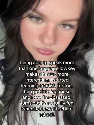 A selfie-style video cover image showcasing a young woman with long dark hair. The woman is looking slightly up and to the side with a neutral expression. Text is overlaid on the image in white letters. The background is out of focus.