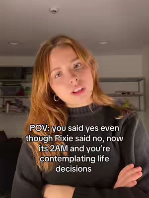 A woman with reddish-blonde hair looks directly at the camera with a neutral expression. Text overlays are positioned over the image, and the background shows an interior with visible shelves and a ceiling light.
