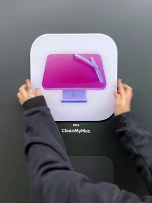 The cover image shows a person holding a square, rounded-corner graphic against a dark background. The graphic features a stylized computer monitor icon with a pink screen and a light blue component at its base. There are two hands holding the graphic from the sides.