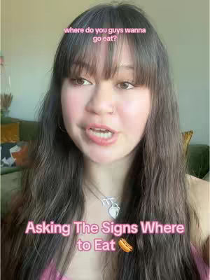 A young woman with long brown hair and bangs is centered in the frame, looking directly at the camera and speaking. Above her head, the text 'where do you guys wanna go eat?' is overlaid in a light pink font. At the bottom, the text 'Asking The Signs Where to Eat' appears in the same font, with a hot dog emoji next to it.