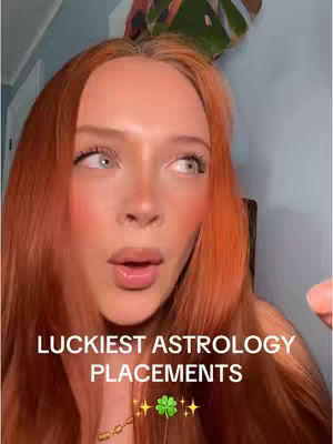 A woman with red hair and light skin is the focus of the image, gazing slightly off to the side with parted lips. Text overlays the bottom portion of the image and includes the phrase "Luckiest Astrology Placements" alongside four leaf clover graphics and stars. The background is blurred, with colors like green, blue, and hints of other colors.