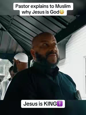 A medium shot captures a middle-aged Black man with a bald head and a neatly trimmed beard, wearing a dark shirt, addressing the camera. Behind him, two men with white skullcaps are partially visible in the blurred background. The image is framed within an indoor space, possibly a shelter or temporary structure, with visible metal roofing above, creating a sense of a casual or informal setting. Text overlays indicate themes of religious dialogue.