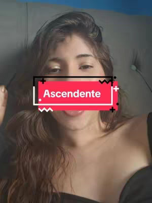 A woman lies on what appears to be a bed or couch, facing the camera. Her tongue is sticking out, and a red rectangle with the word "Ascendente" overlaid partially covers her face. The background is blue and gray, suggesting a casual, indoor setting.