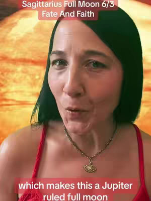 A woman with dark hair and a red top is centered, speaking. The background features an orange, blurred celestial design. Text overlays read 'Sagittarius Full Moon 6/3 Fate And Faith' and a lower banner states 'which makes this a Jupiter ruled full moon'. She wears a necklace with a unique pendant.