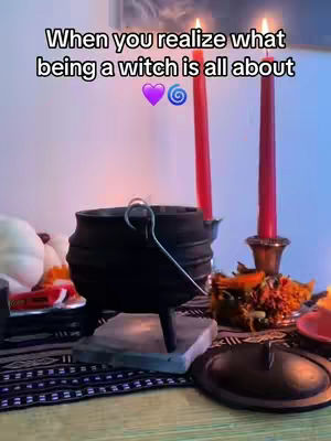 The cover image shows a room setting, with a table covered in a patterned cloth. A black cauldron sits on a square stone, near two red candles in ornate holders and various decorations, including a small bowl of potpourri, a plate with a lid, and a white pumpkin.