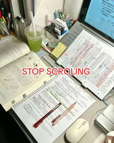 A top-down shot of a desk setup with open textbooks, a laptop displaying a screen, a cup of green beverage, and various stationery items like pens and a mouse, all giving off a study ambiance.