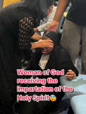 A woman is kneeling with her eyes covered by another person's hand. Text overlayed reads: 'Woman of God receiving the impartation of the Holy Spirit'. The image has a shallow depth of field, with the woman in focus and others blurred in the background. The color scheme is muted, with the woman having fair skin and dark hair.