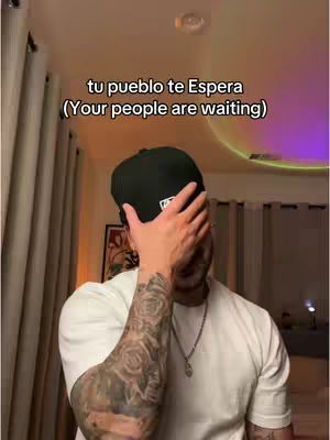 A man in a white t-shirt and a black cap is covering his face with his right hand. Tattoos are visible on his left arm. White text is overlayed on the image.