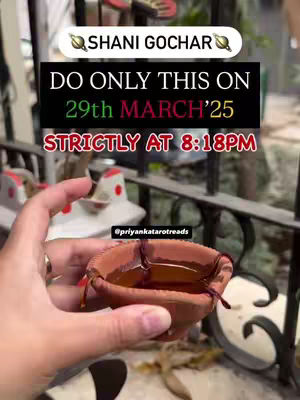 A hand holding a small, clay lamp filled with liquid, likely oil. The background is blurred, showing a window or outdoor setting, with a text overlay providing instructions and the phrase "Shani Gochar". The image is warmly lit, emphasizing the lamp and the text instructions.