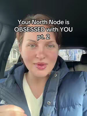 A woman with fair skin and short brown hair is centered in the frame. She is wearing a blue puffer jacket over a white, v-neck shirt. The background shows a car interior with a glimpse of a street view outside, the face is pretty well lit, with text overlaid on the image.