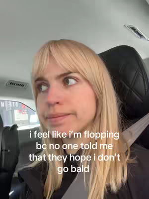 The cover image shows a close-up shot of a woman in a car looking slightly to the left. She has blonde hair with a fringe, fair skin, and is wearing a black jacket. The background features the interior of a vehicle, including a seat and a window. Text overlayed on the image contains the phrases expressing feelings of not fitting in and the wish for her not to lose her hair.