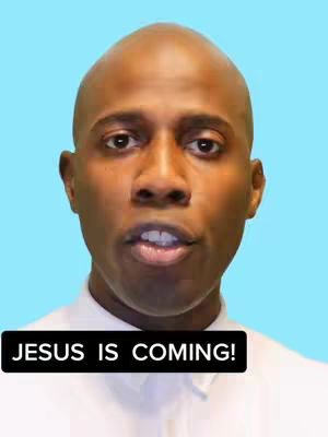 A face close-up of a Black man with a shaved head, looking directly at the camera. He wears a white collared shirt against a bright blue background. A black banner across the bottom of the image displays the text "JESUS IS COMING!"
