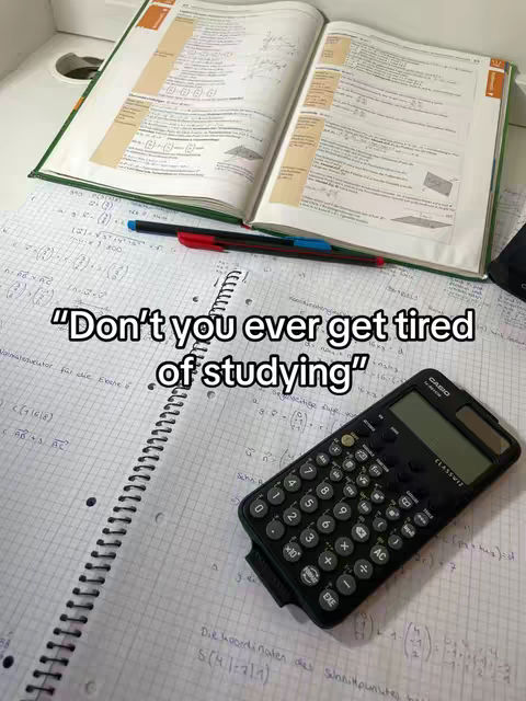 The cover image shows a close-up of a desk with an open textbook, a spiral notebook with handwritten notes, a calculator, and two pens. The text overlayed across the image says, "Don't you ever get tired of studying"