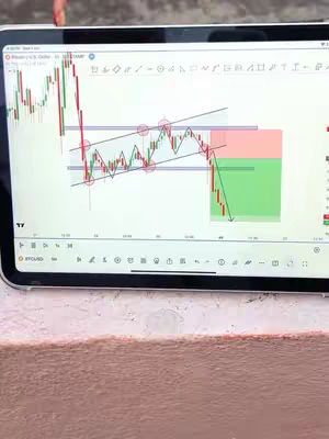 A close-up shot of a tablet displaying a Bitcoin/USDT trading chart. The screen shows a candlestick graph with red and green candles, trend lines, and potential support and resistance levels, which are analyzed. The tablet is set against a light-colored surface. The scene suggests an analysis of cryptocurrency trading.