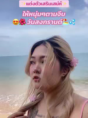 A woman with blonde hair and pink hair clips stands on a beach with the ocean and sky in the background. Text overlays are present at the top of the image.
