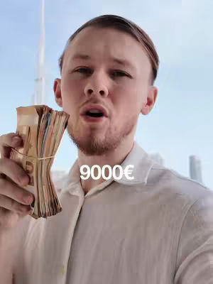 A man with fair skin holds a bundle of money in his left hand. The money appears to be a mix of various denominations, suggesting Euros. He is looking upwards with his mouth open. Behind him is a bright sky, and a building or structure that extends upwards. The number "9000€" is superimposed in white.
