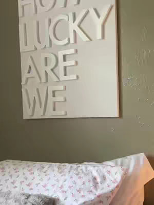 The cover image shows a wall hanging with white, three-dimensional letters that say 'HOW LUCKY ARE WE'. Below the hanging is a bed with a patterned pillow.