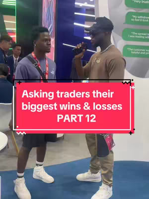 Two young men are talking in an indoor trade show setting. The man on the right is holding a microphone.