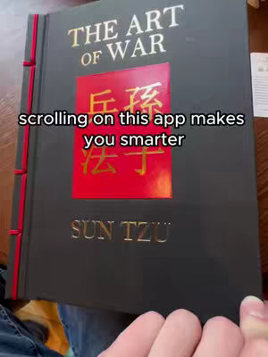 The cover image shows a close-up of a book tilted slightly to the side. The book is bound in dark gray with red accents on the spine. The title "THE ART OF WAR" in gold letters is prominently displayed at the top. A red rectangular section in the center features Chinese characters in gold. Below, the author's name, SUN TZU, is printed in gold. Text overlayed on the image reads "scrolling on this app makes you smarter". The book is held in a dark, slightly blurred setting, with hands visible at the bottom of the frame.
