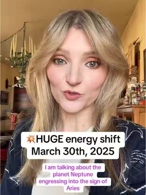 A woman with blonde hair and makeup is centered in a well-lit room, facing the camera. Overlaid text in a white box shares information about an upcoming astrological event. The background includes hints of a chandelier and other decorative elements.