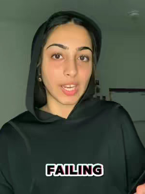 A young woman wearing a black hoodie and a hood is the central focus. The background is blurred with a slightly green hue, and the text 'FAILING' is prominently displayed in bold, sans-serif font. The overall composition is a medium shot focusing on the youth's facial expression.