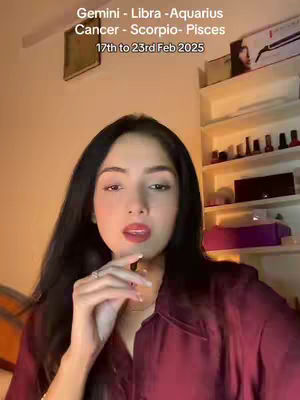 A woman with long black hair and a burgundy shirt is the main focus. The background includes shelves with various items. Text overlays at the top state astrological signs and dates.